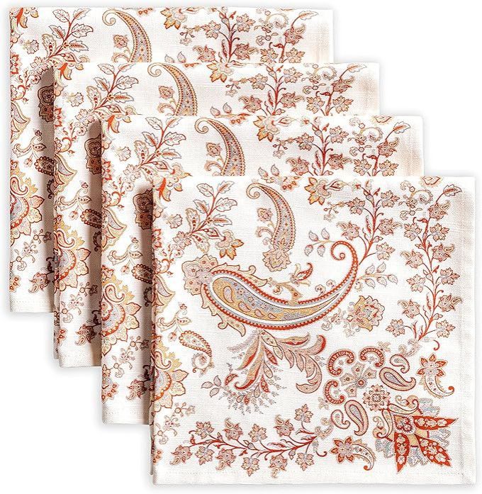 Four folded white napkins with a coral and beige paisley floral pattern