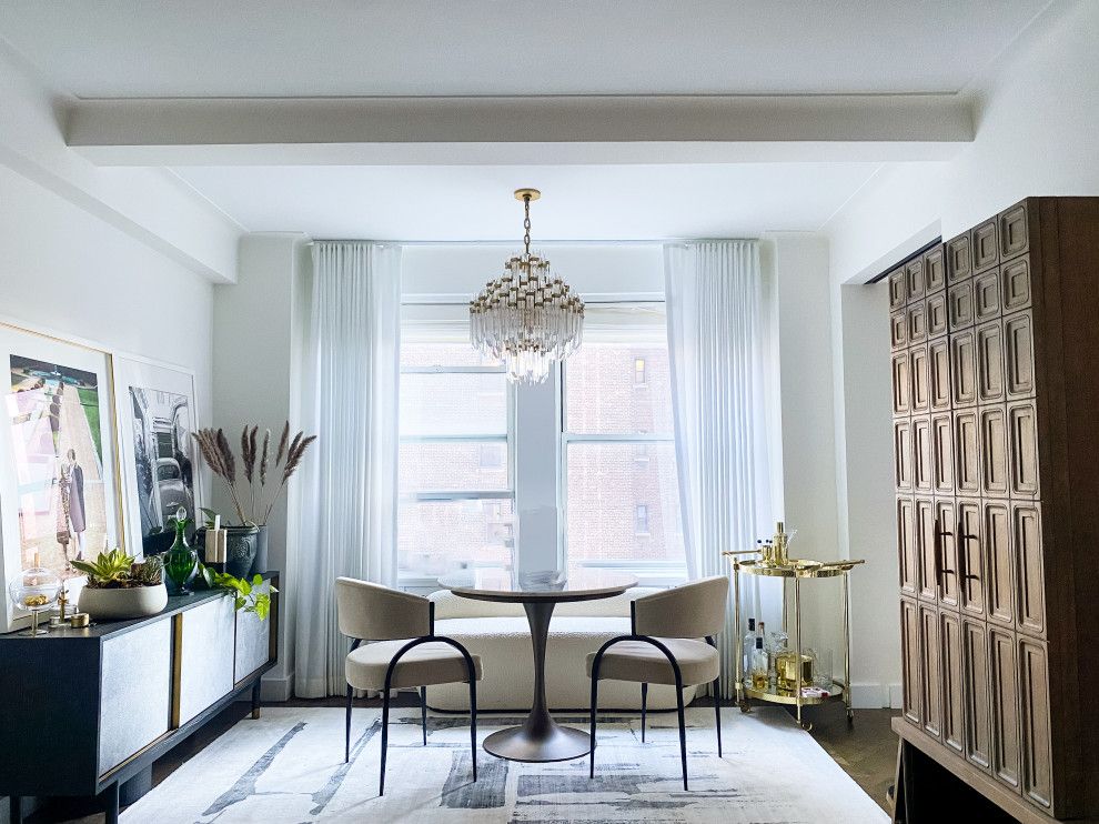 Bright modern dining room with round table, two chairs, chandelier, and patterned wood cabinet