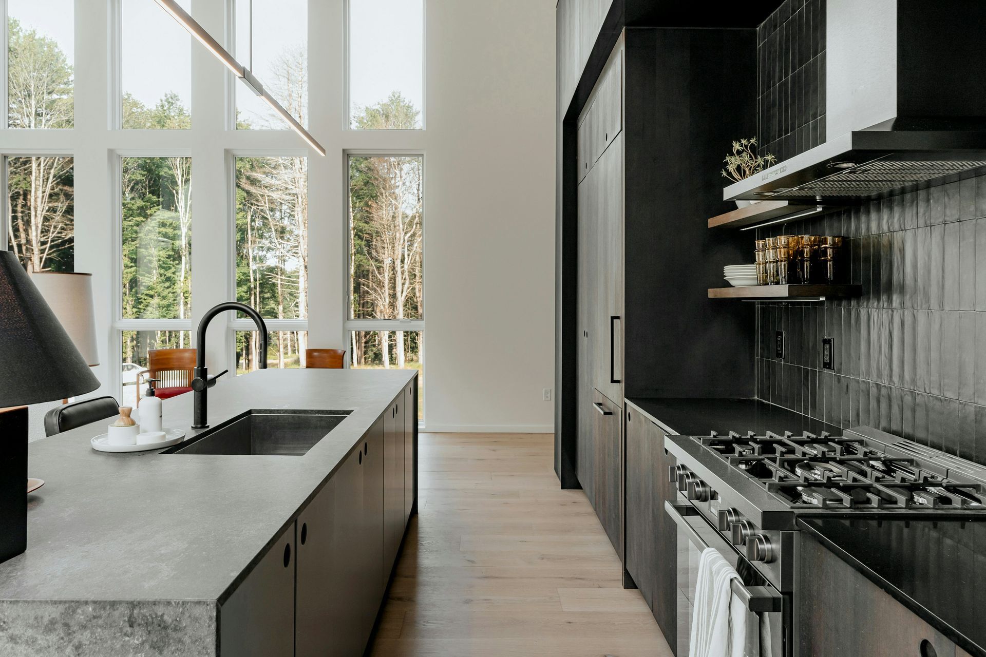 Modern black-and-white kitchen with an island, large windows, and stainless steel appliances.