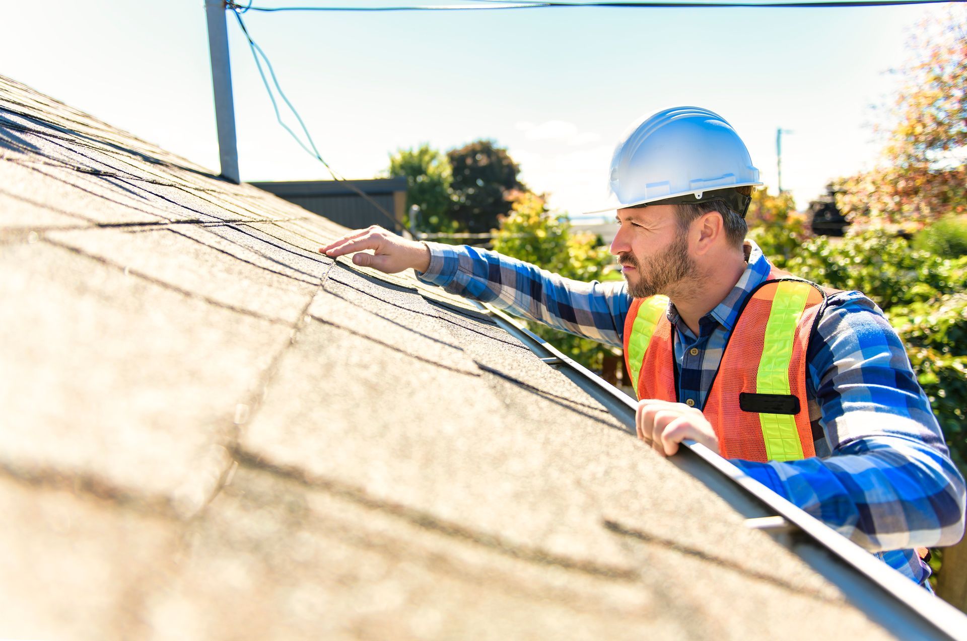 Roof inspector in safety vest examining shingles for damage and wear. Roof inspector in safety vest examining shingles for damage and wear.