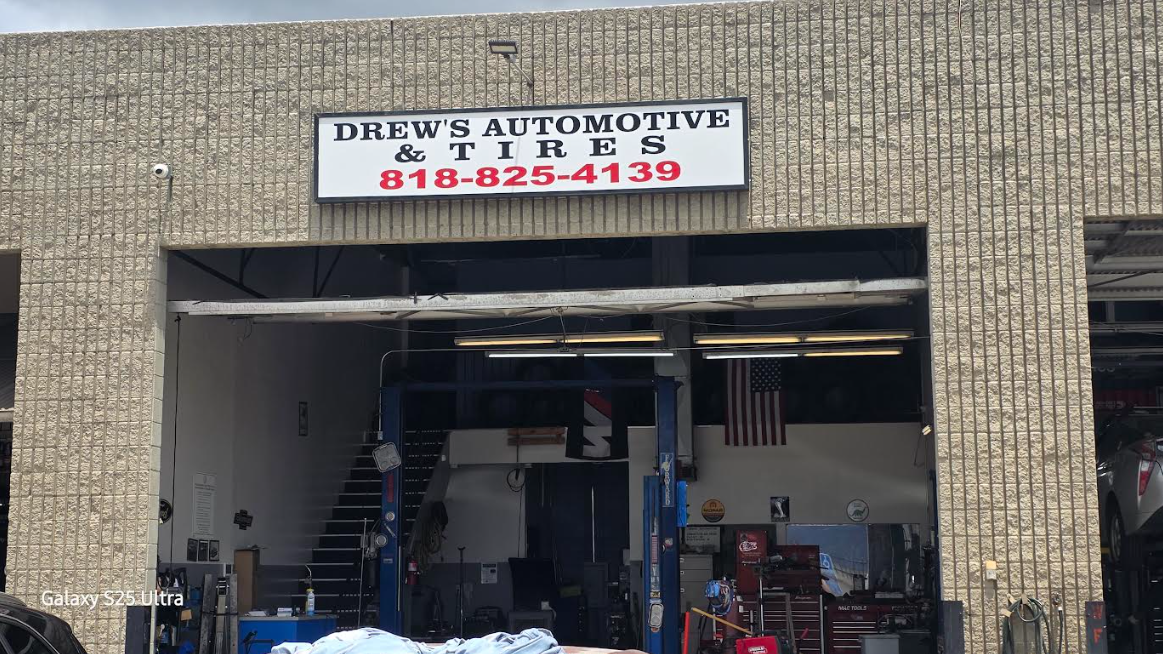 Black car with hood open in a garage, revealing the engine bay.