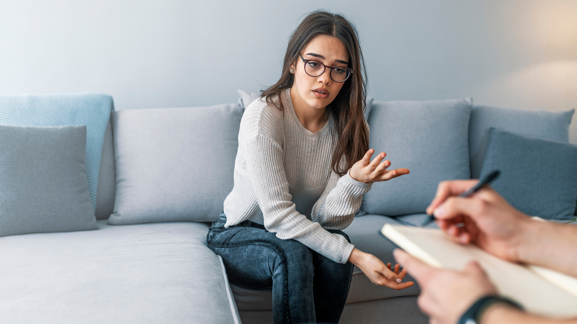 Smiling couple embracing on a couch during a counseling session with a therapist nearby