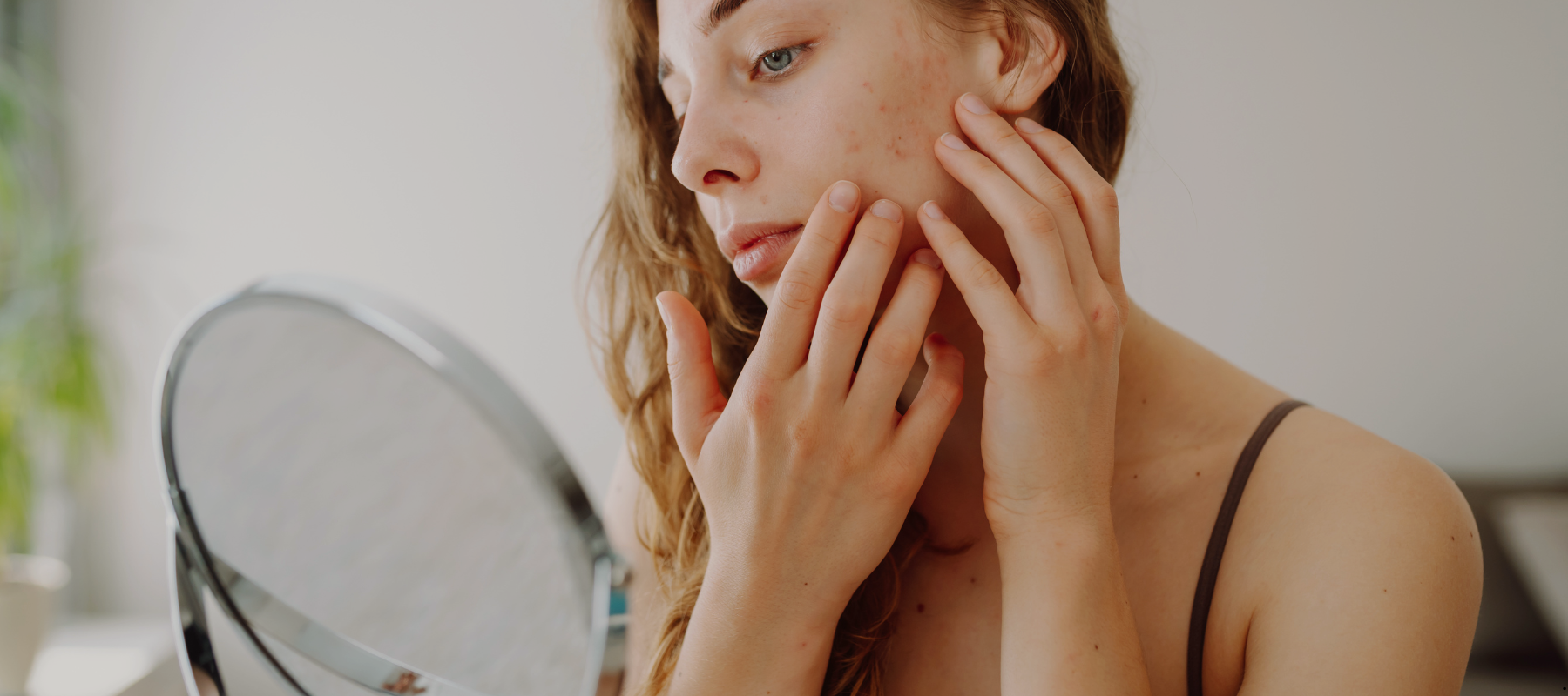 Woman with blemishes looking at her skin in the mirror