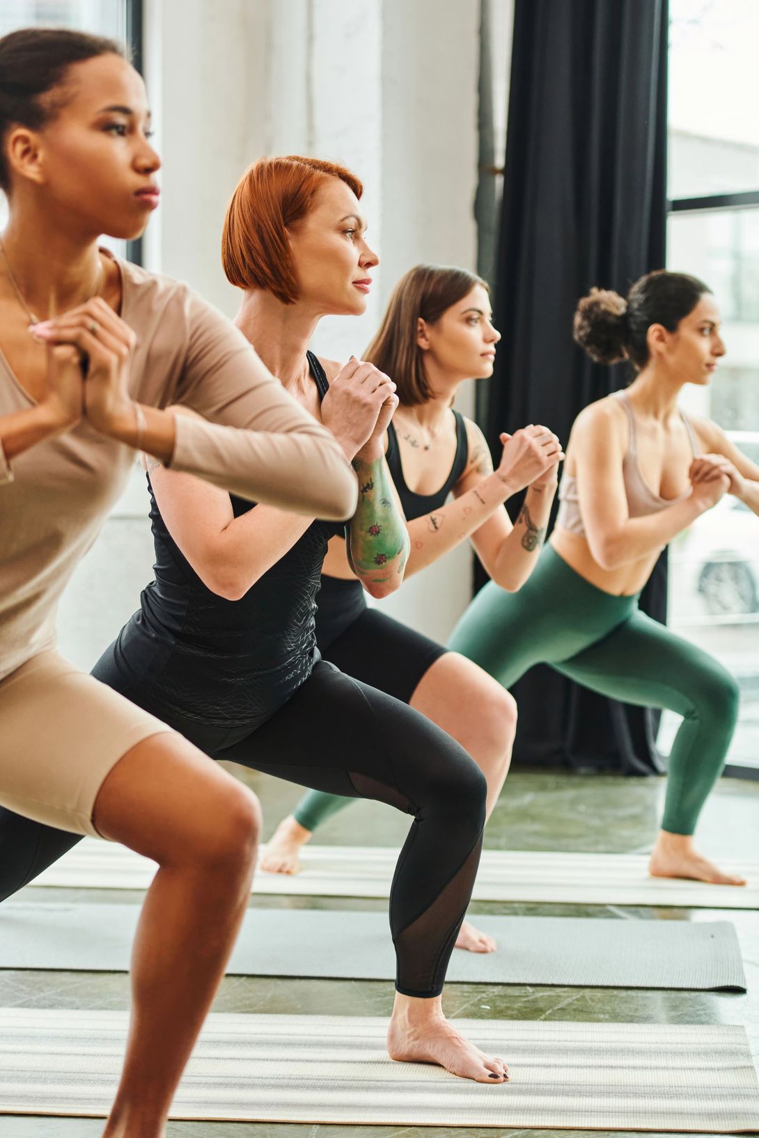 Persone che mantengono posizioni yoga in uno studio luminoso durante una lezione di fitness di gruppo.