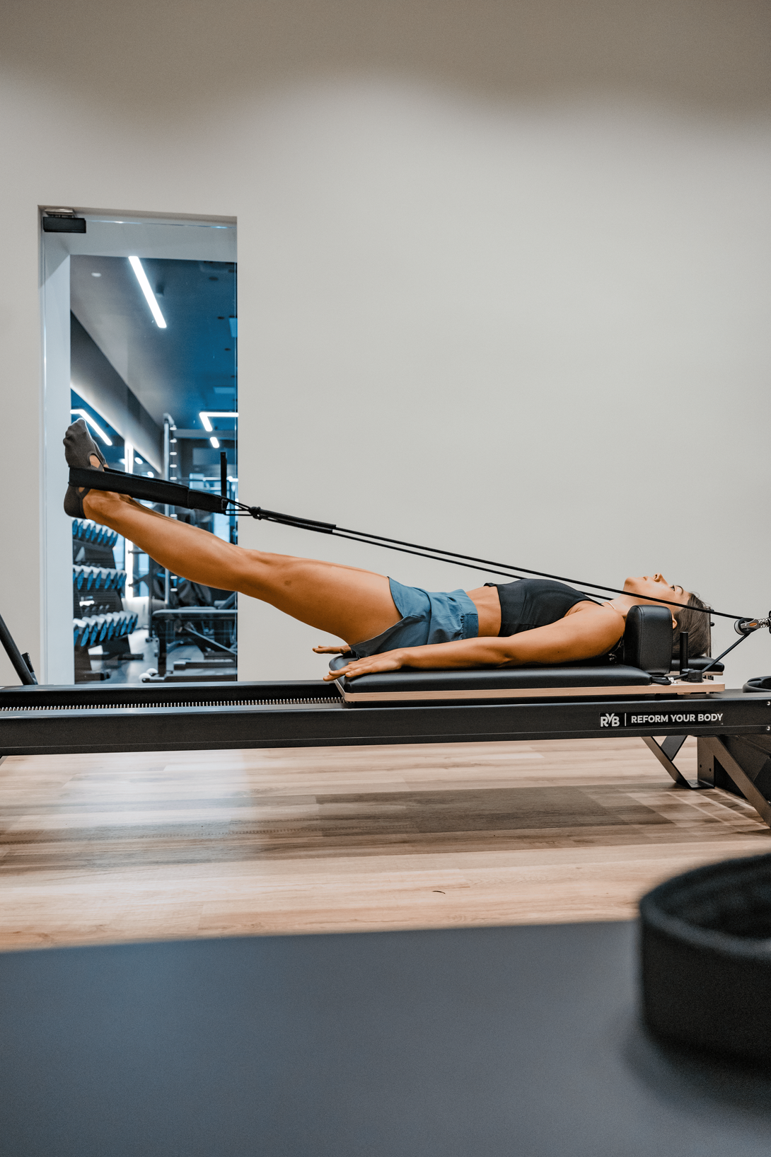 File di manubri neri allineati in una palestra luminosa vicino a una finestra
