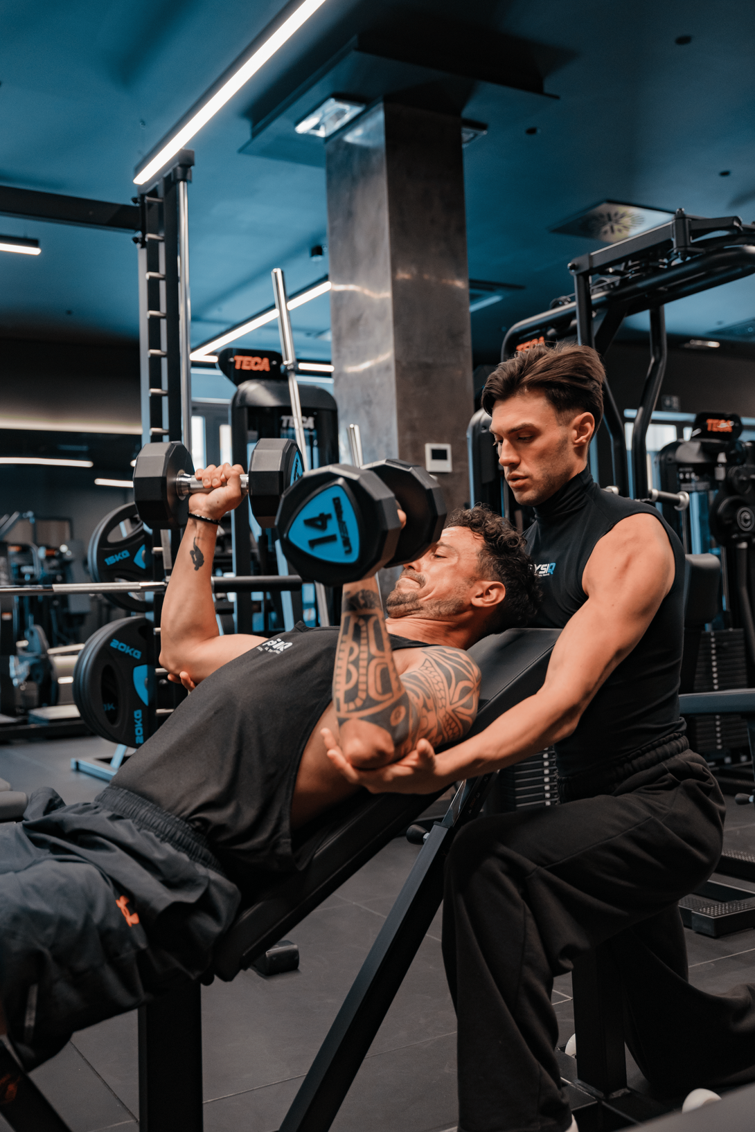 Manubrio sul pavimento della palestra con attrezzi da allenamento sfocati sullo sfondo.