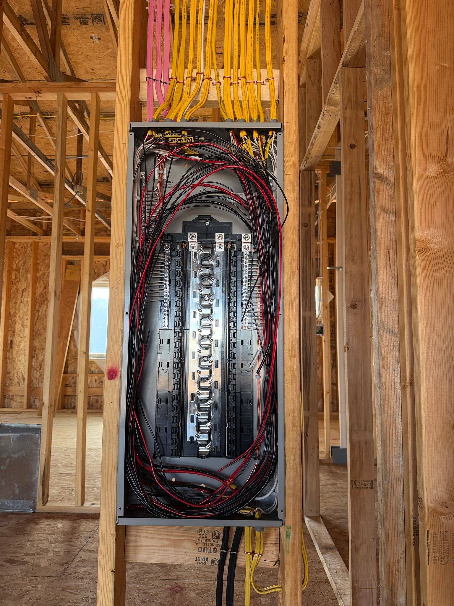 Electrical panel with exposed wiring installed in a framed wall under construction