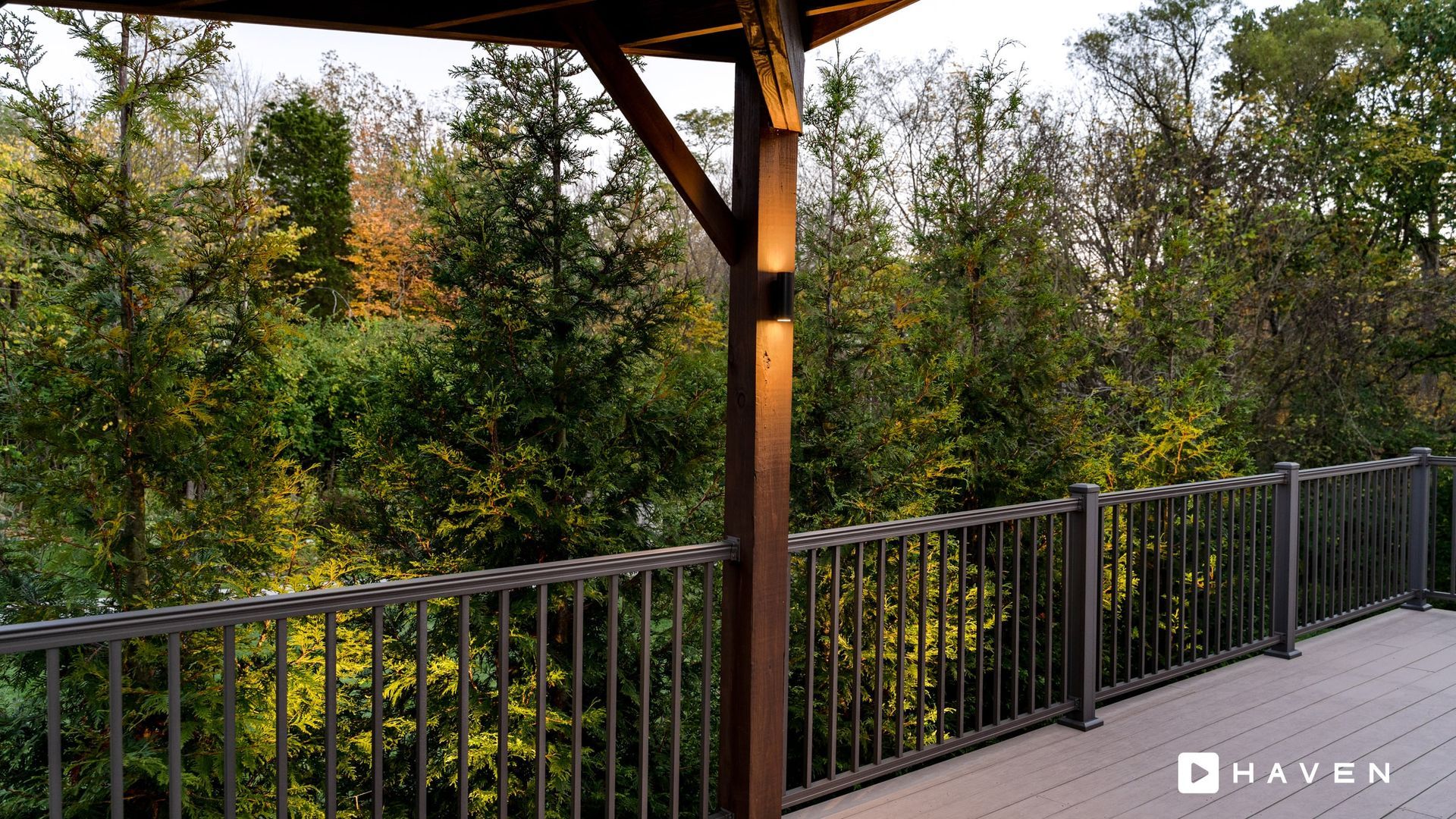 A wooden deck with a metal railing overlooking a forest.