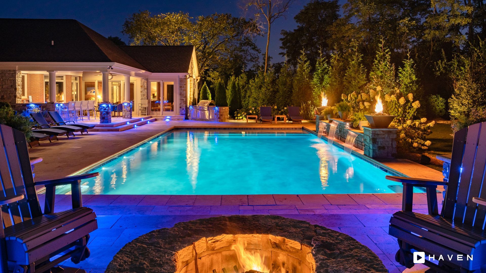 A large swimming pool with a fire pit in the middle of it