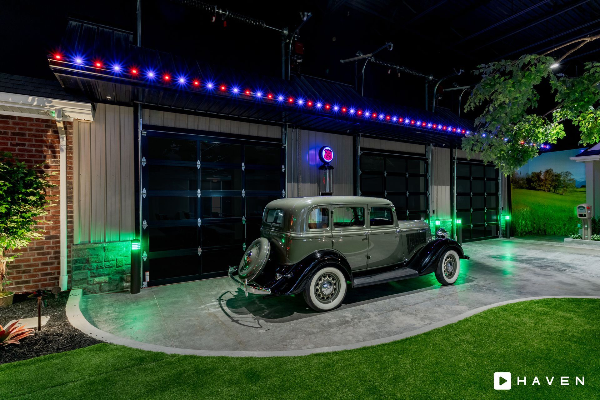 An old car is parked in front of a garage with christmas lights.