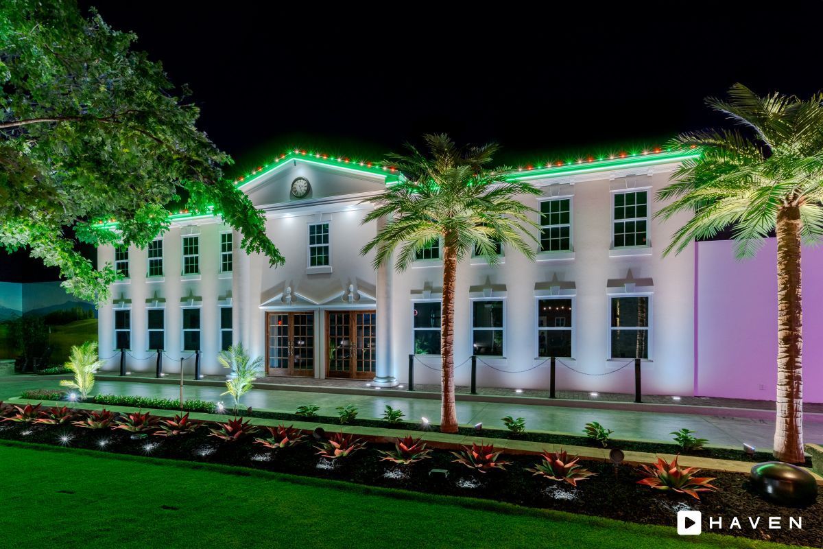A large white building with green and pink lights on it