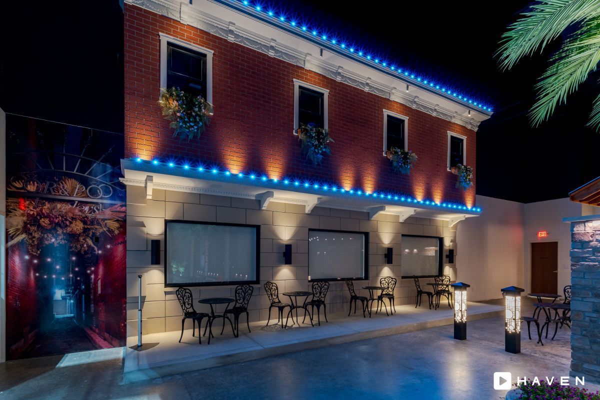 A building with tables and chairs in front of it at night.