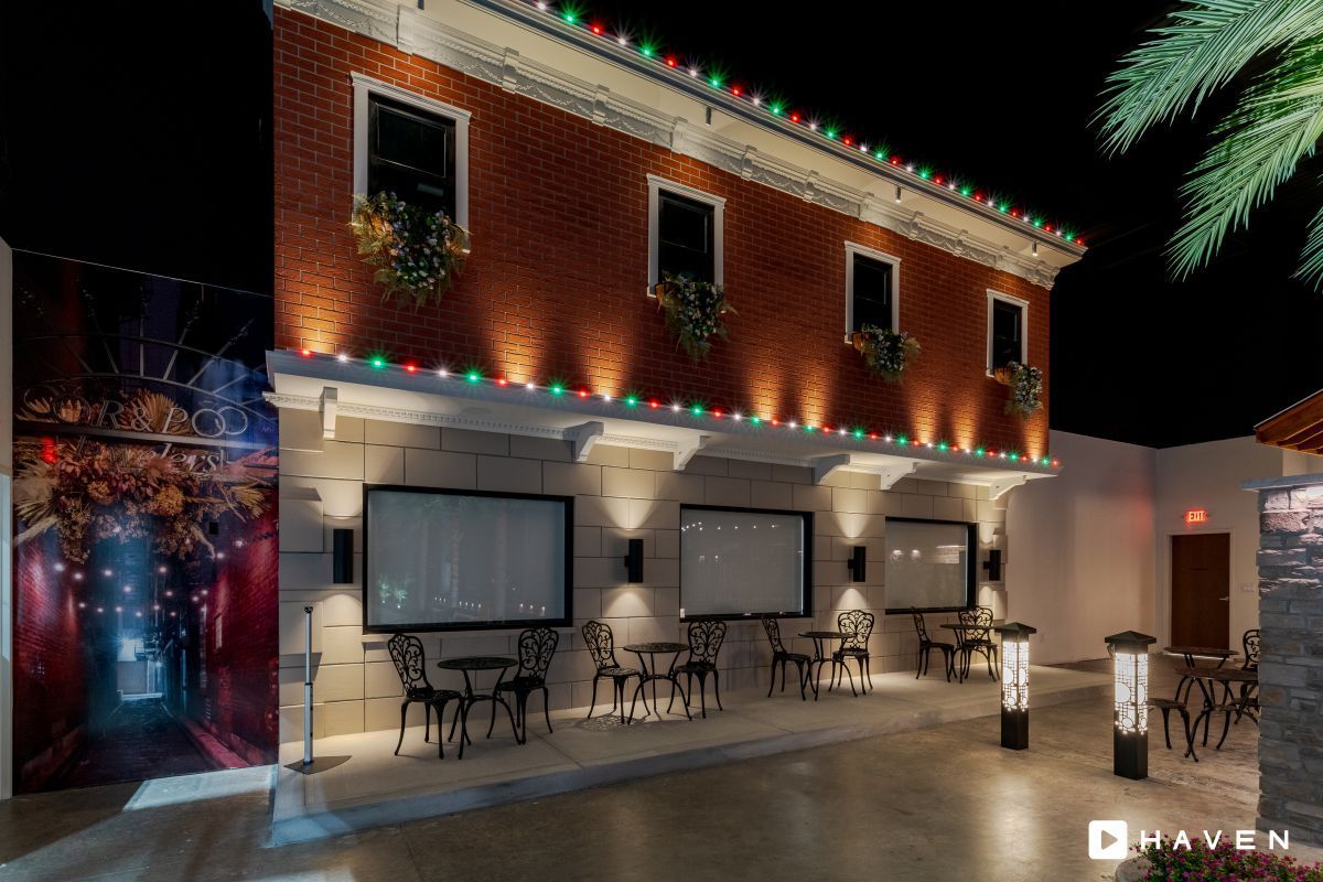 A brick building with tables and chairs in front of it at night.