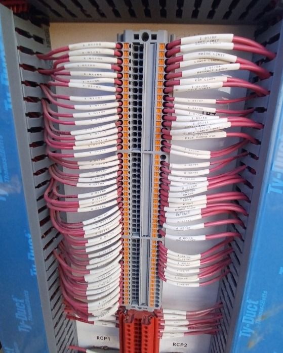 Electrical panel with numerous red and white wires connected to terminal blocks.