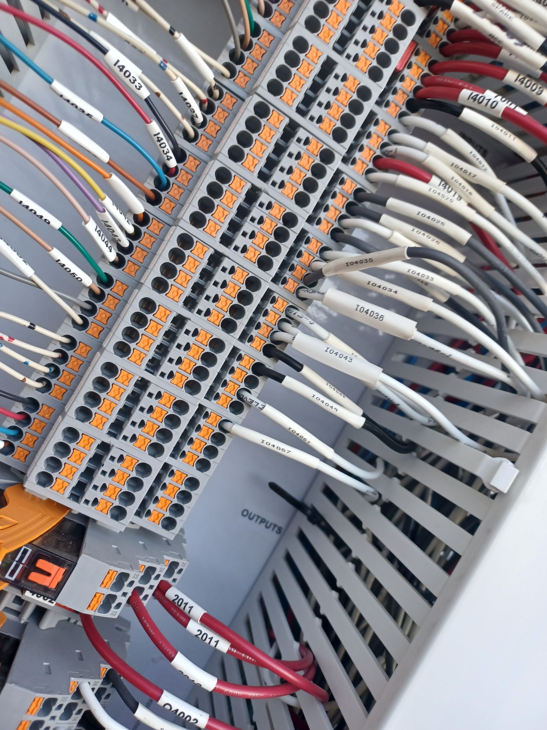 Wires connected to orange terminal blocks inside a control panel.