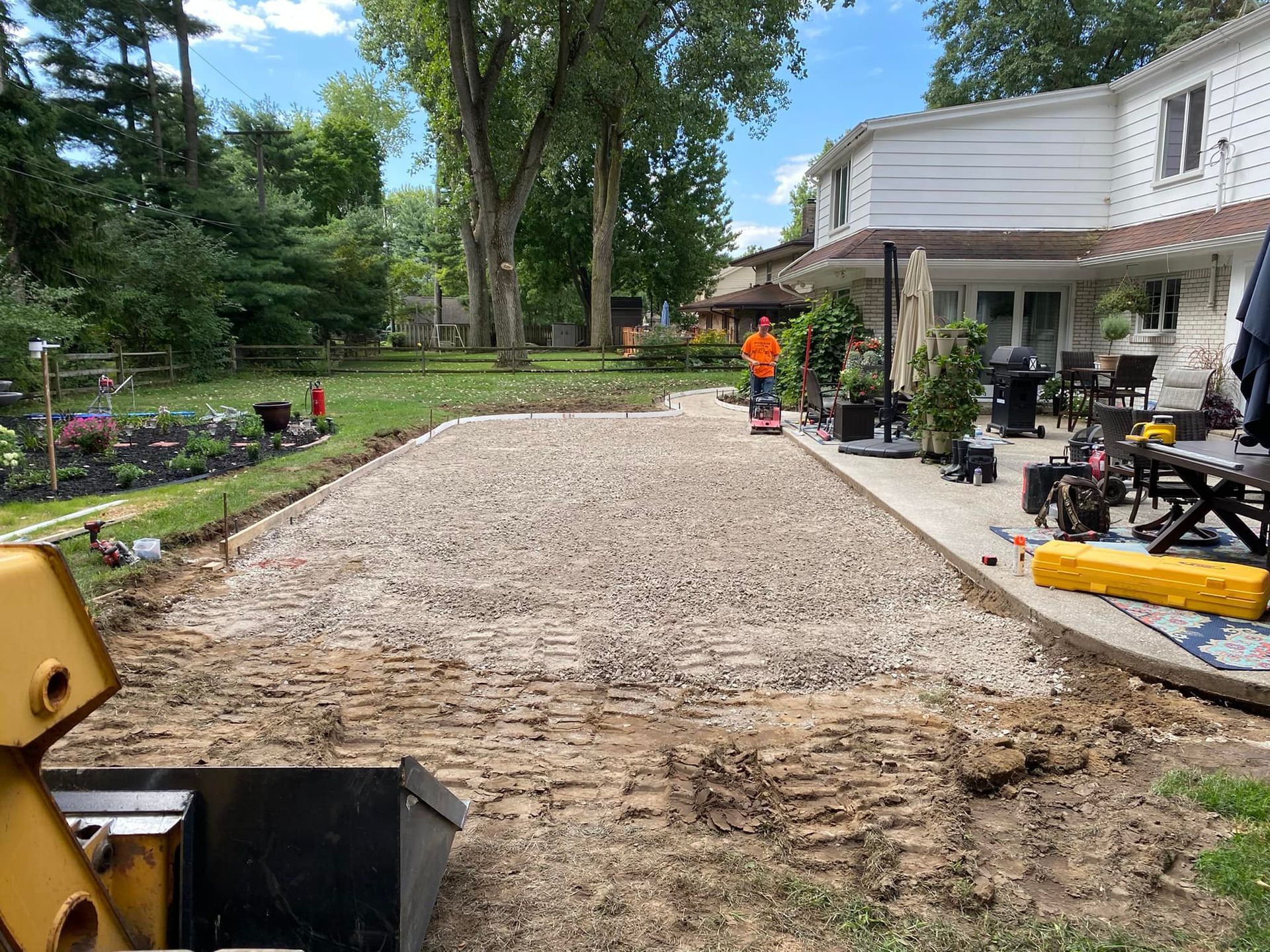 A man is working on a driveway in front of a house.