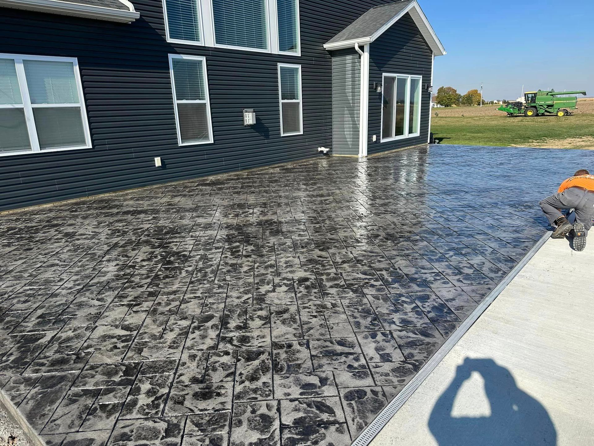 A man is working on a concrete patio in front of a house.