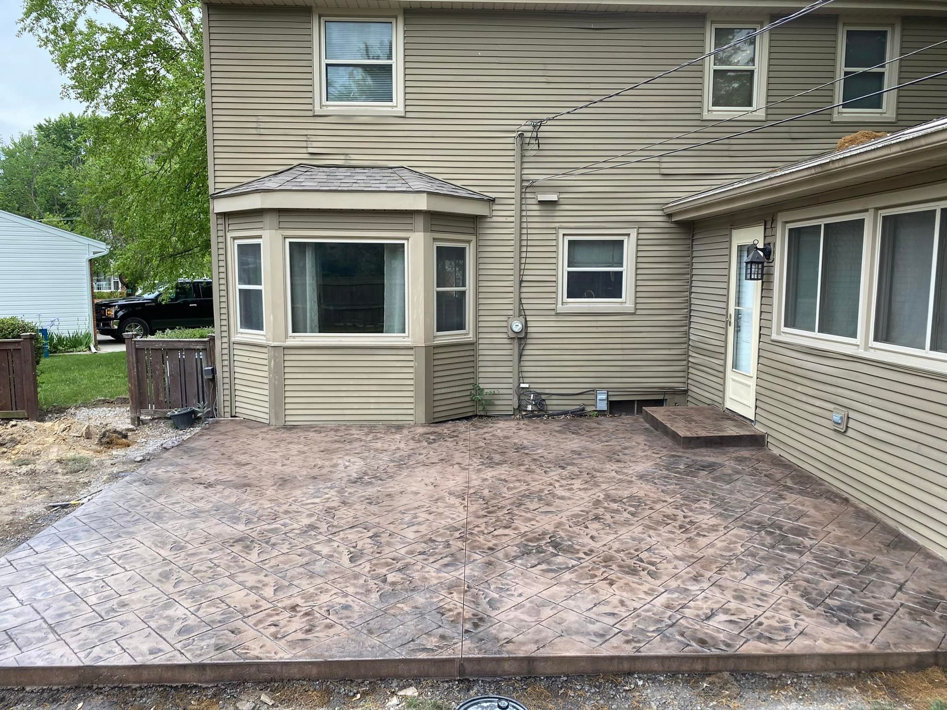 The back of a house with a concrete patio in front of it.