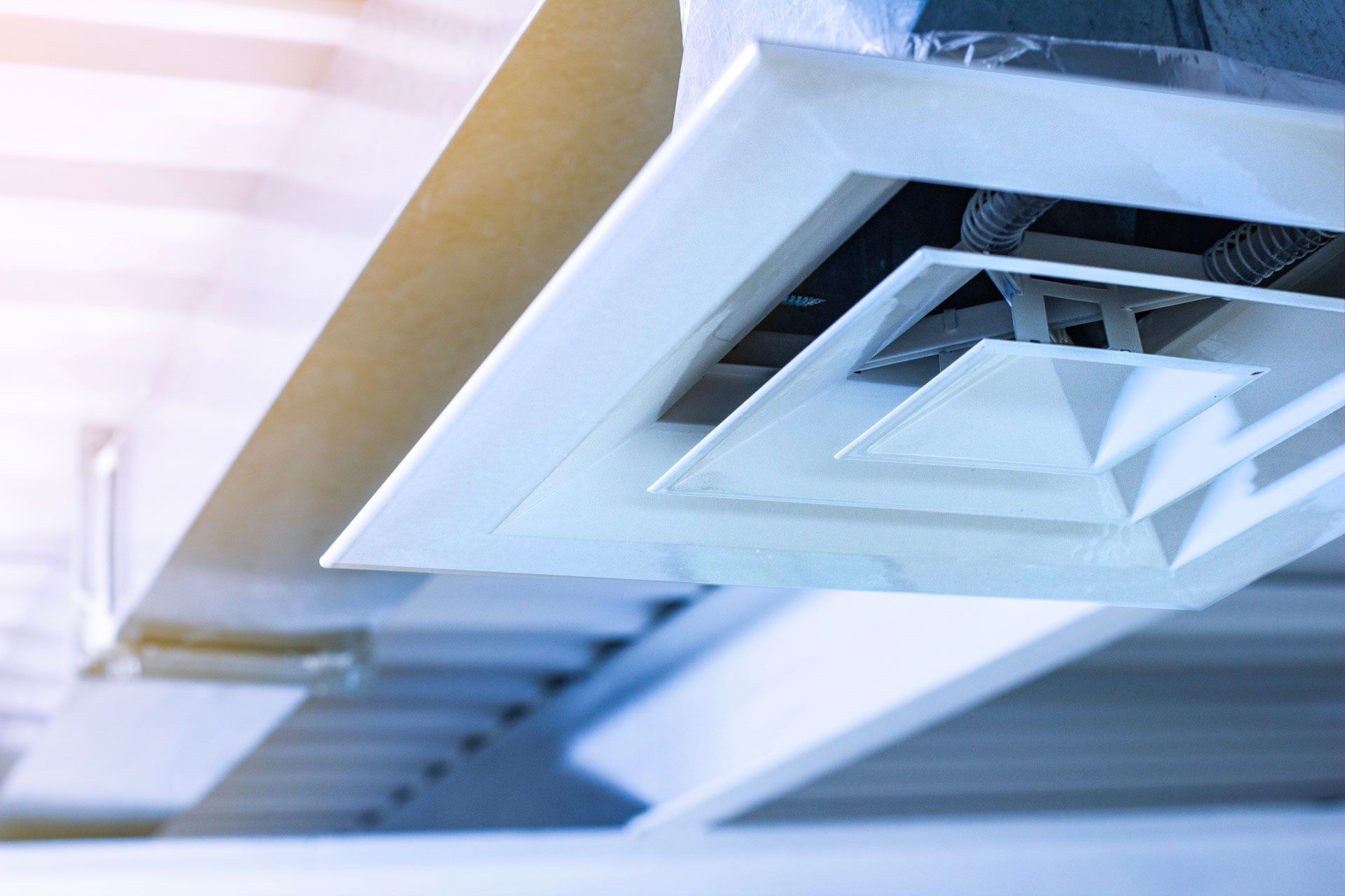 Close-up of a white air vent on a ceiling, part of a ventilation system.