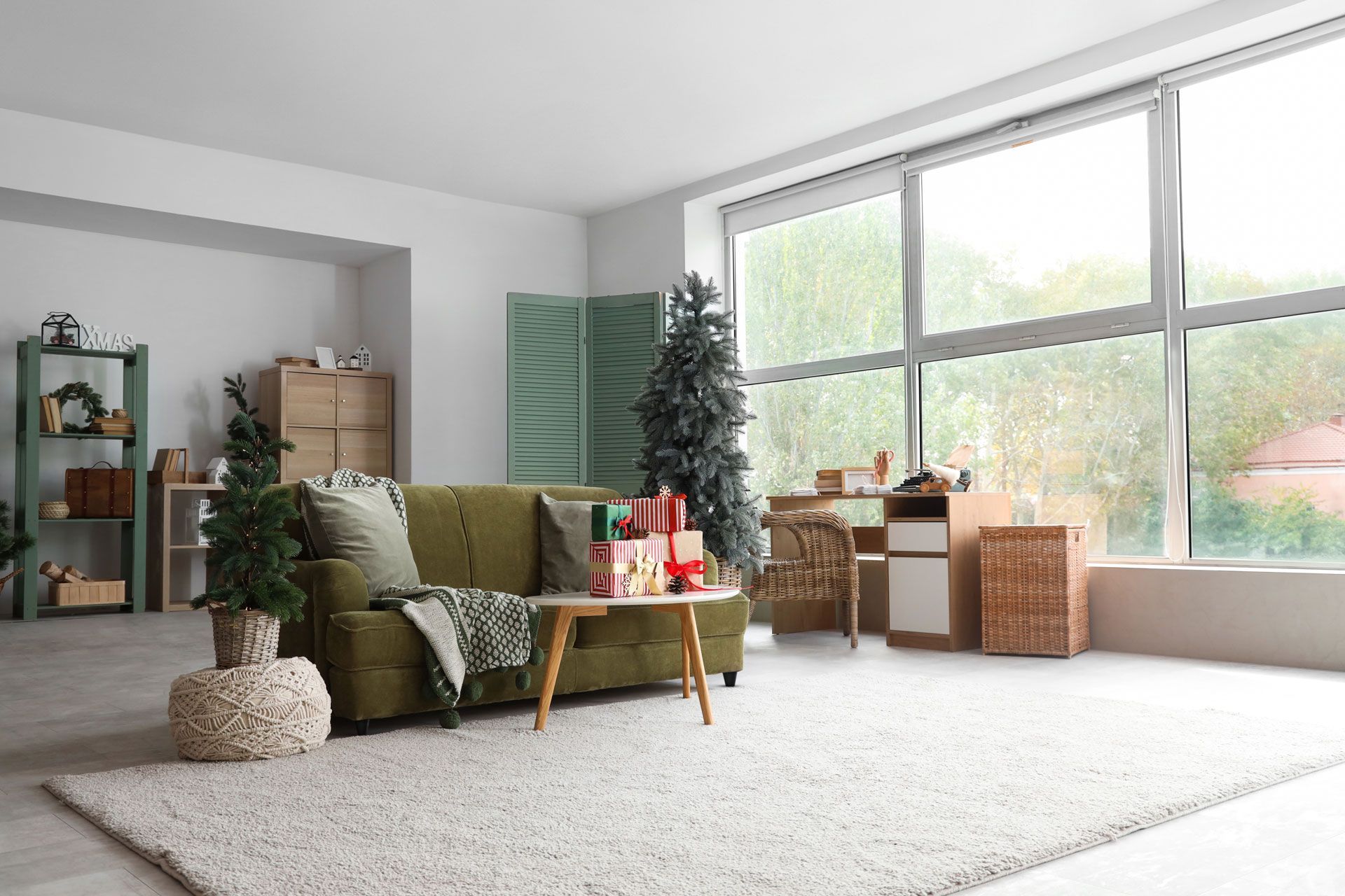 Living room with green sofa, Christmas tree, gifts, rug, and large window.