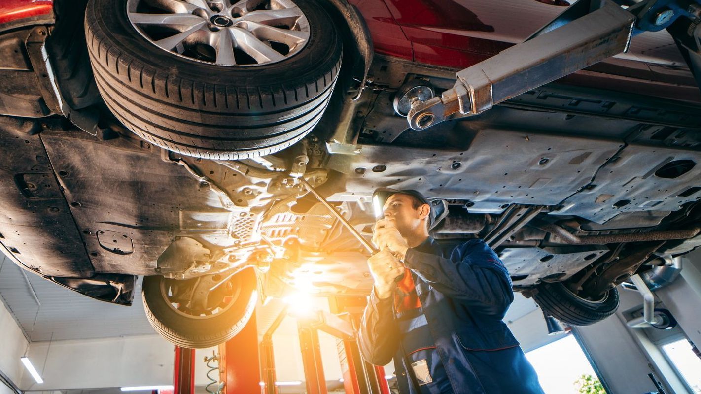 A man is working under a car in a garage.