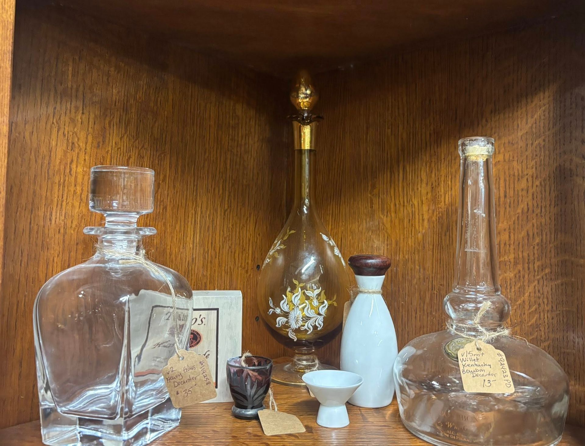 Bottles and small items on a wooden shelf. Includes clear, amber and white glass