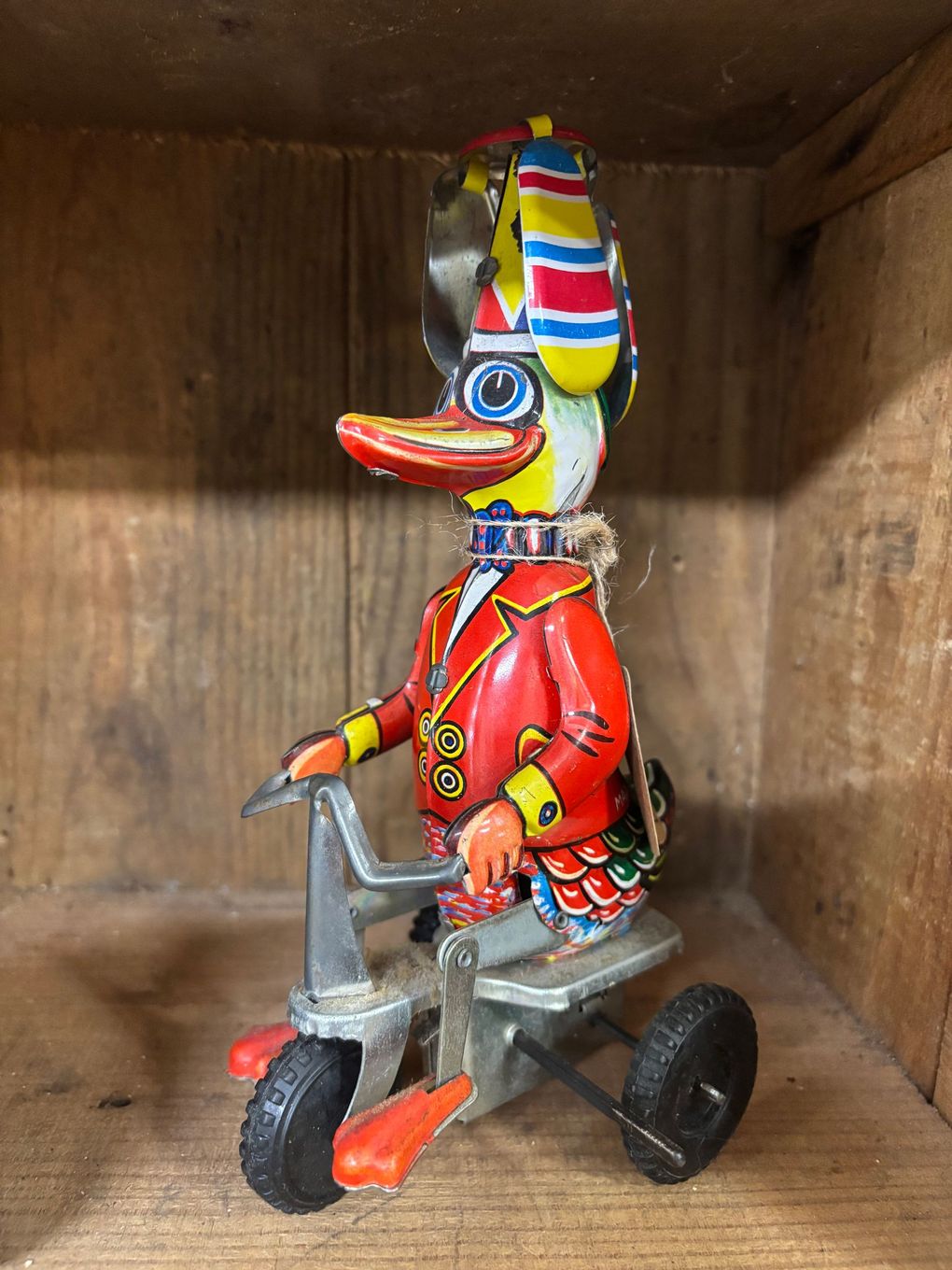 Tin duck on a tricycle, wearing a red jacket and striped hat. 