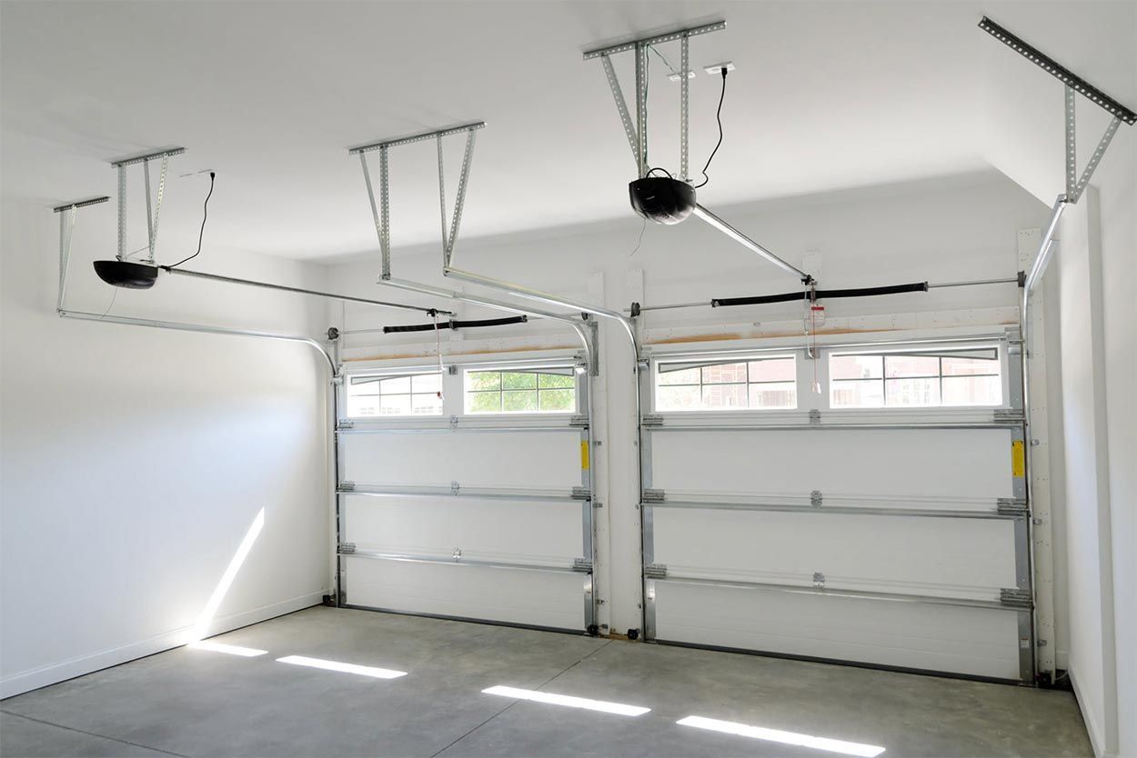 An empty garage with two garage doors and a ceiling fan.