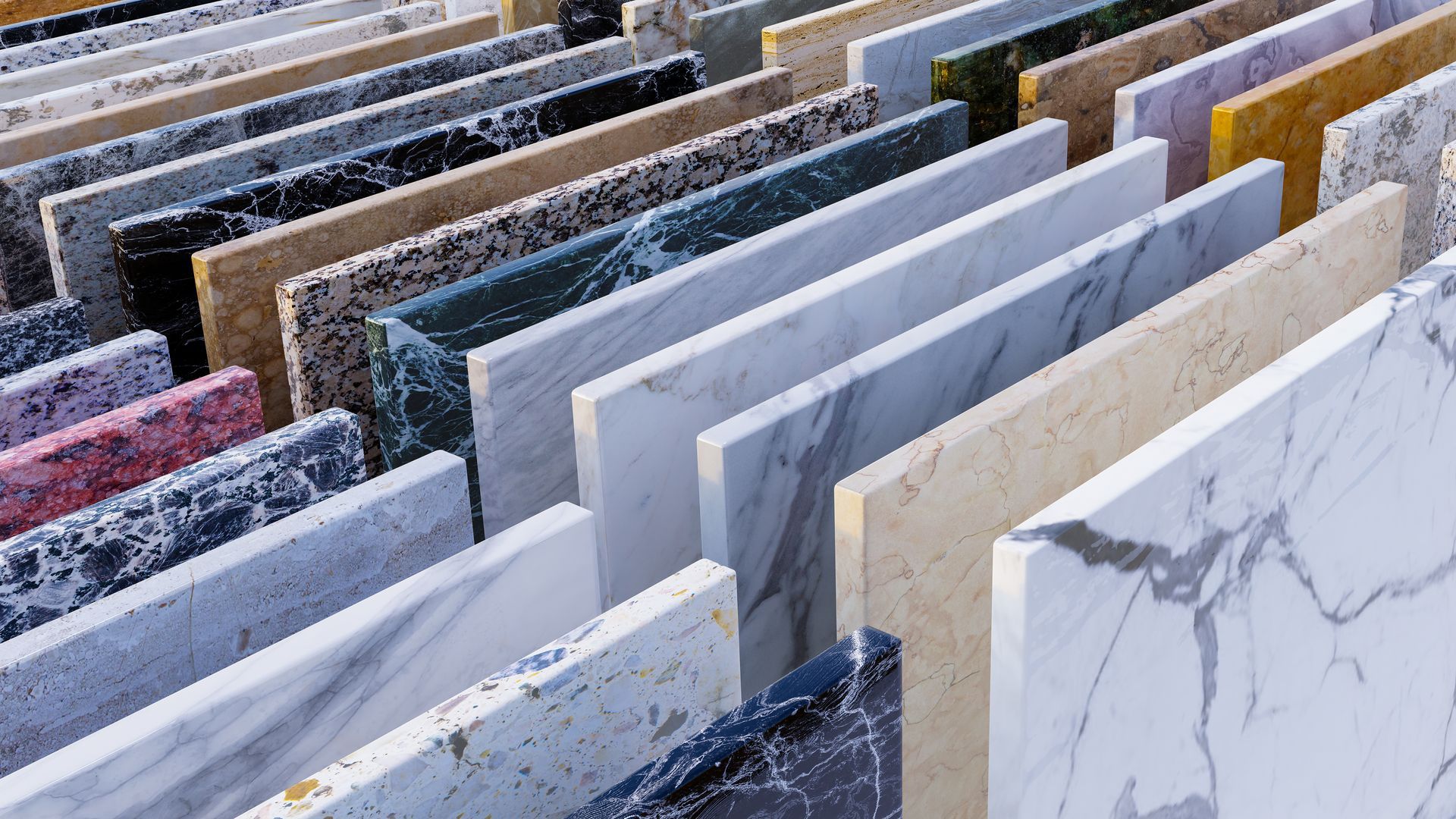 Rows of colorful stone and marble slabs displayed in a showroom, including white, gray, and patterned samples