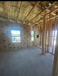 Unfinished room with drywall, exposed insulation, wooden framing, and a window letting in daylight.