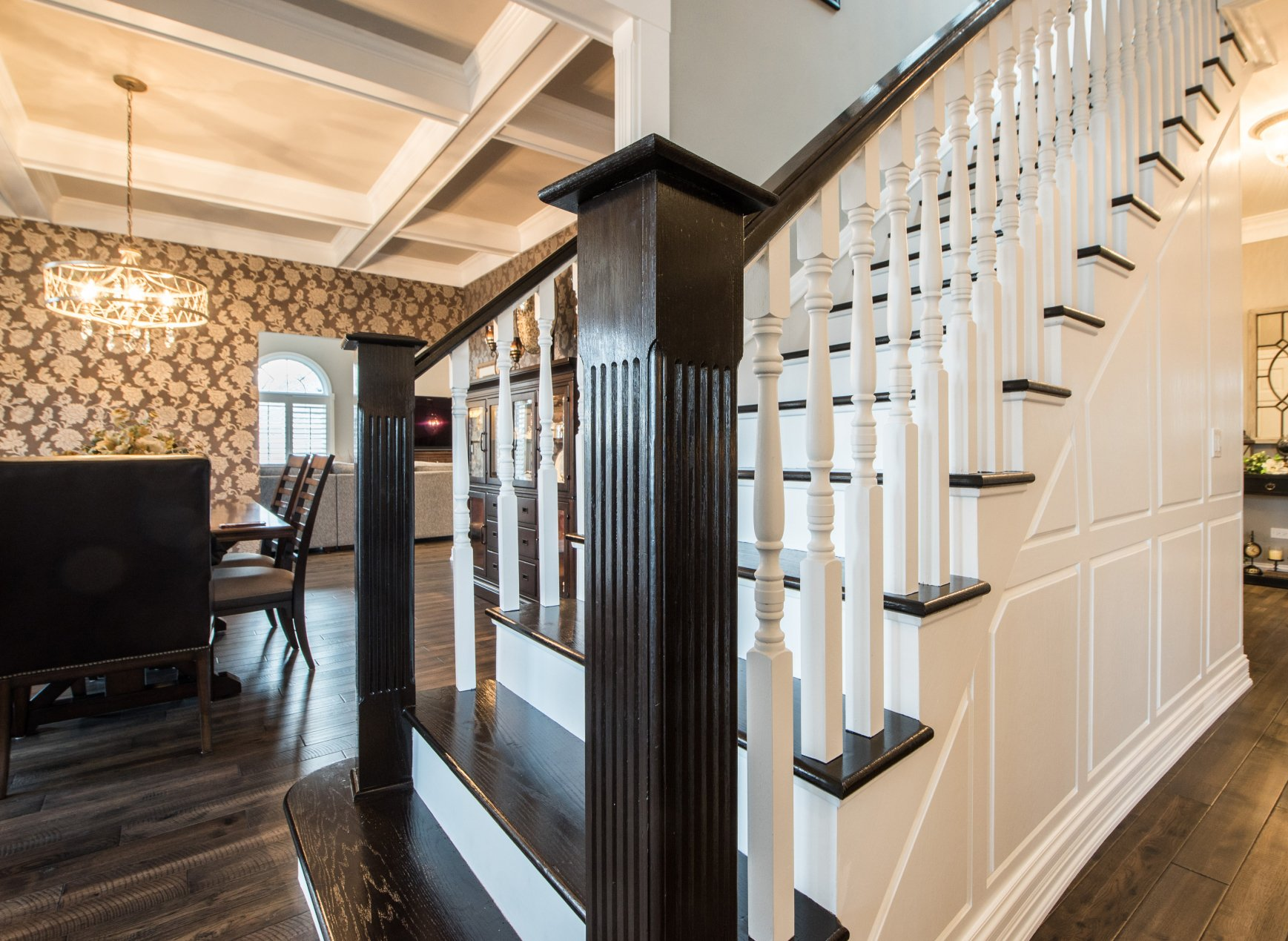 Elegant foyer with dark wood staircase, white balusters, and stone accent wall