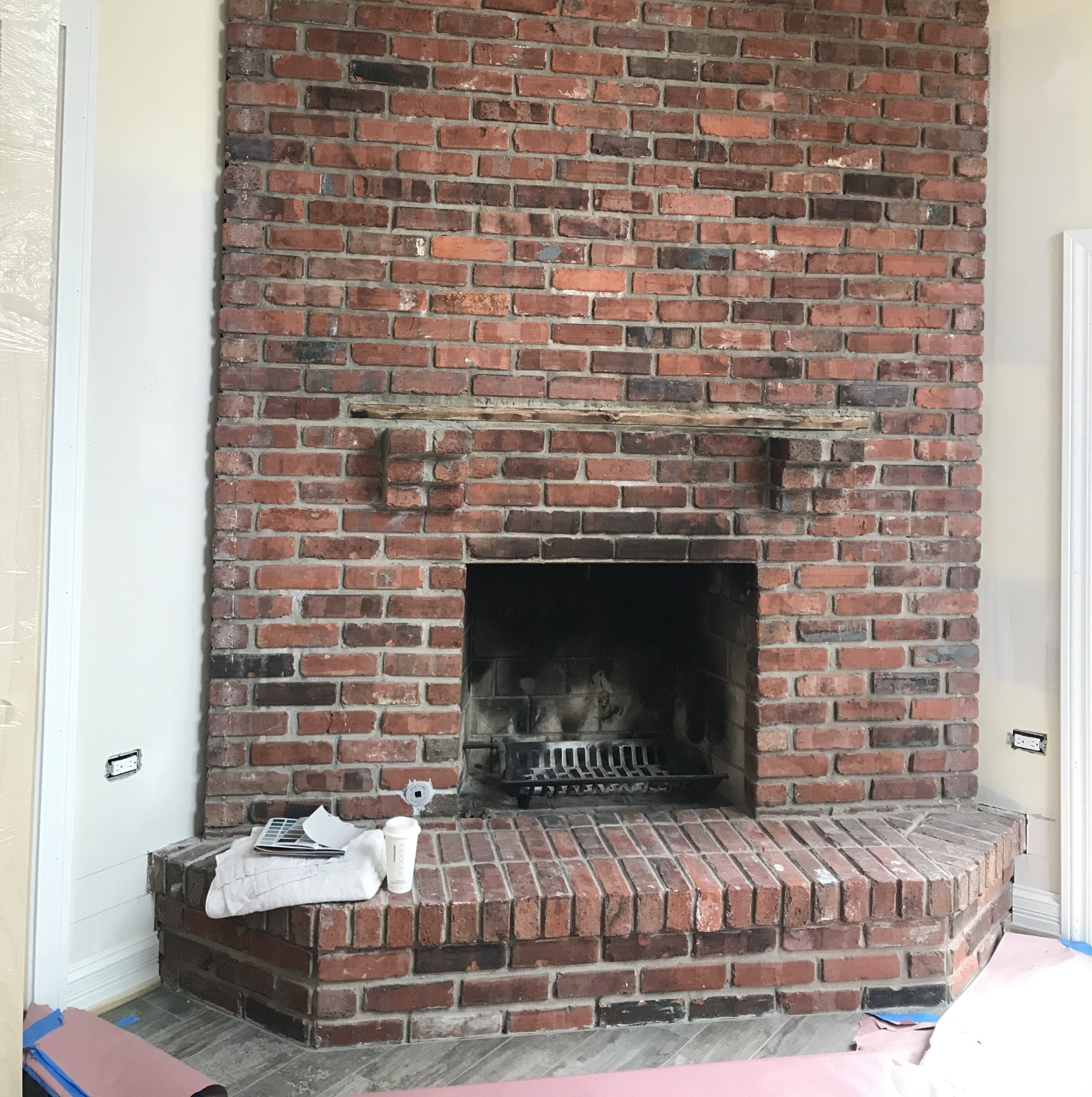 Brick fireplace with a white mantel surround and built-in hearth in a room with white walls.