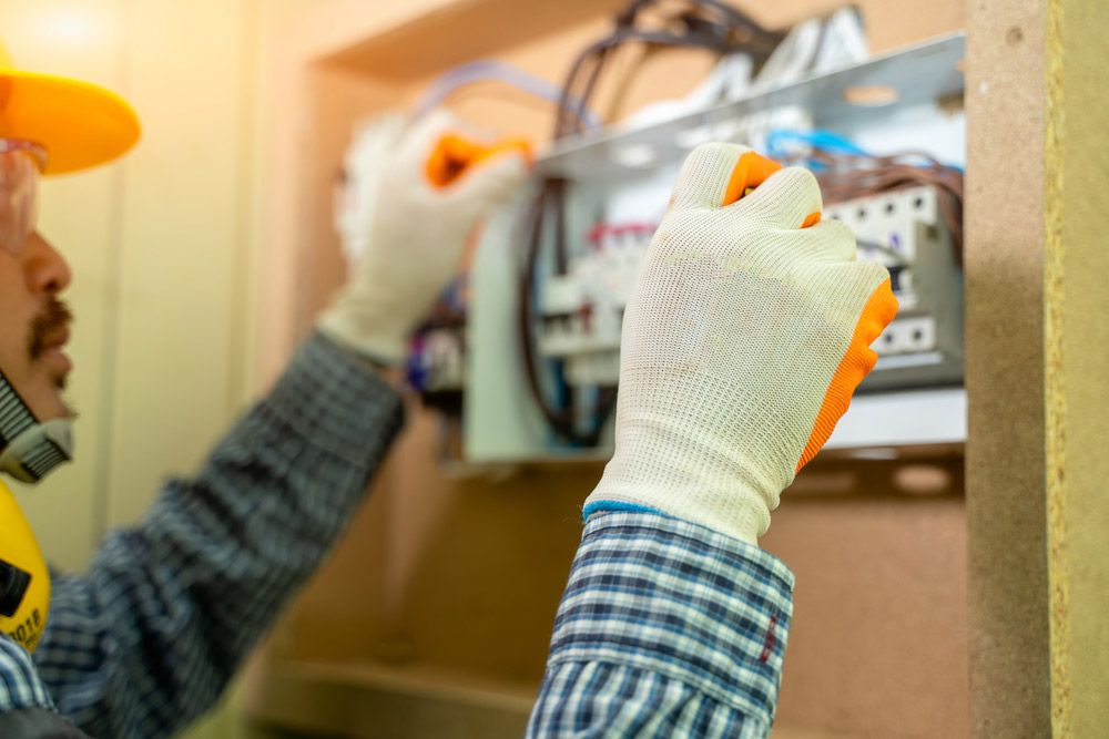 An Electrician is Working on an Electrical Box in a Room — Atherton Electrical in Mareeba, QLD