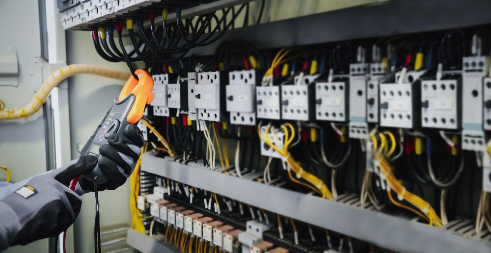 A Man is Working on an Electrical Panel With a Clamp — Atherton Electrical in Tablelands, QLD