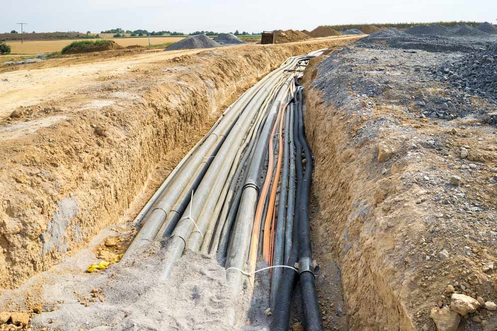A Bunch of Pipes Are Laying in the Dirt in a Trench — Atherton Electrical in Atherton, QLD