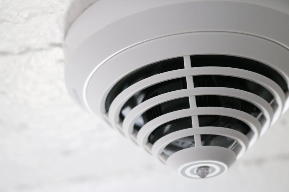 White Smoke Detector Mounted on a Textured White Ceiling — Atherton Electrical in Yungaburra, QLD