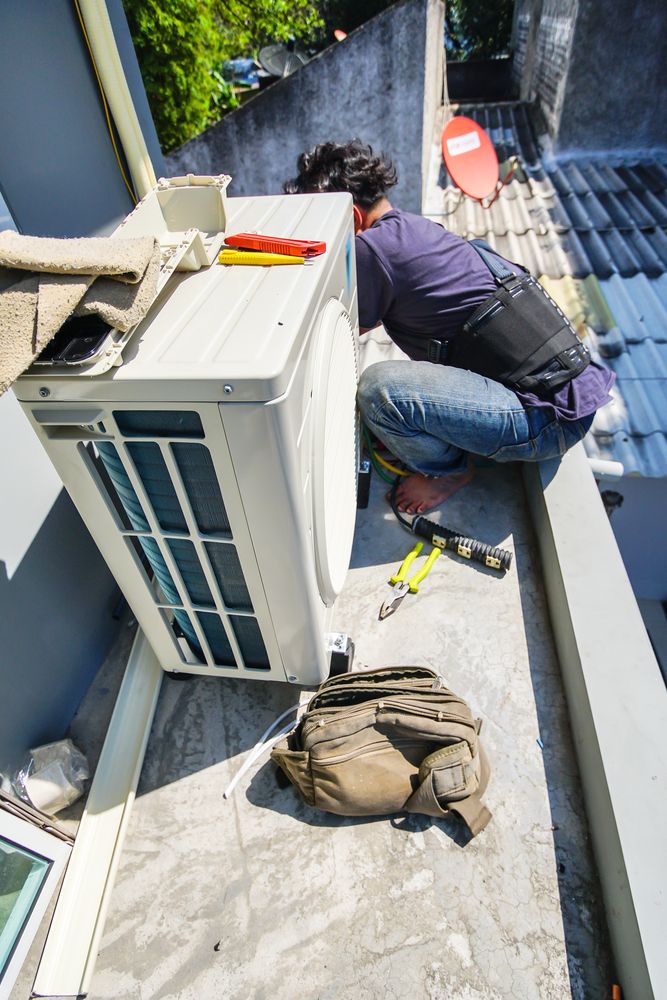 A Worker Installs an Ac Unit on a Rooftop — Atherton Electrical in Malanda, QLD