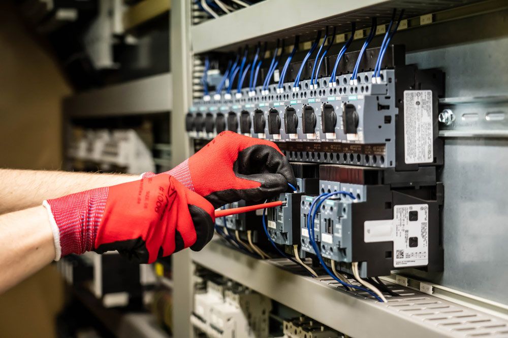 A Person Wearing Red Gloves is Working on an Electrical Panel — Atherton Electrical in Atherton, QLD