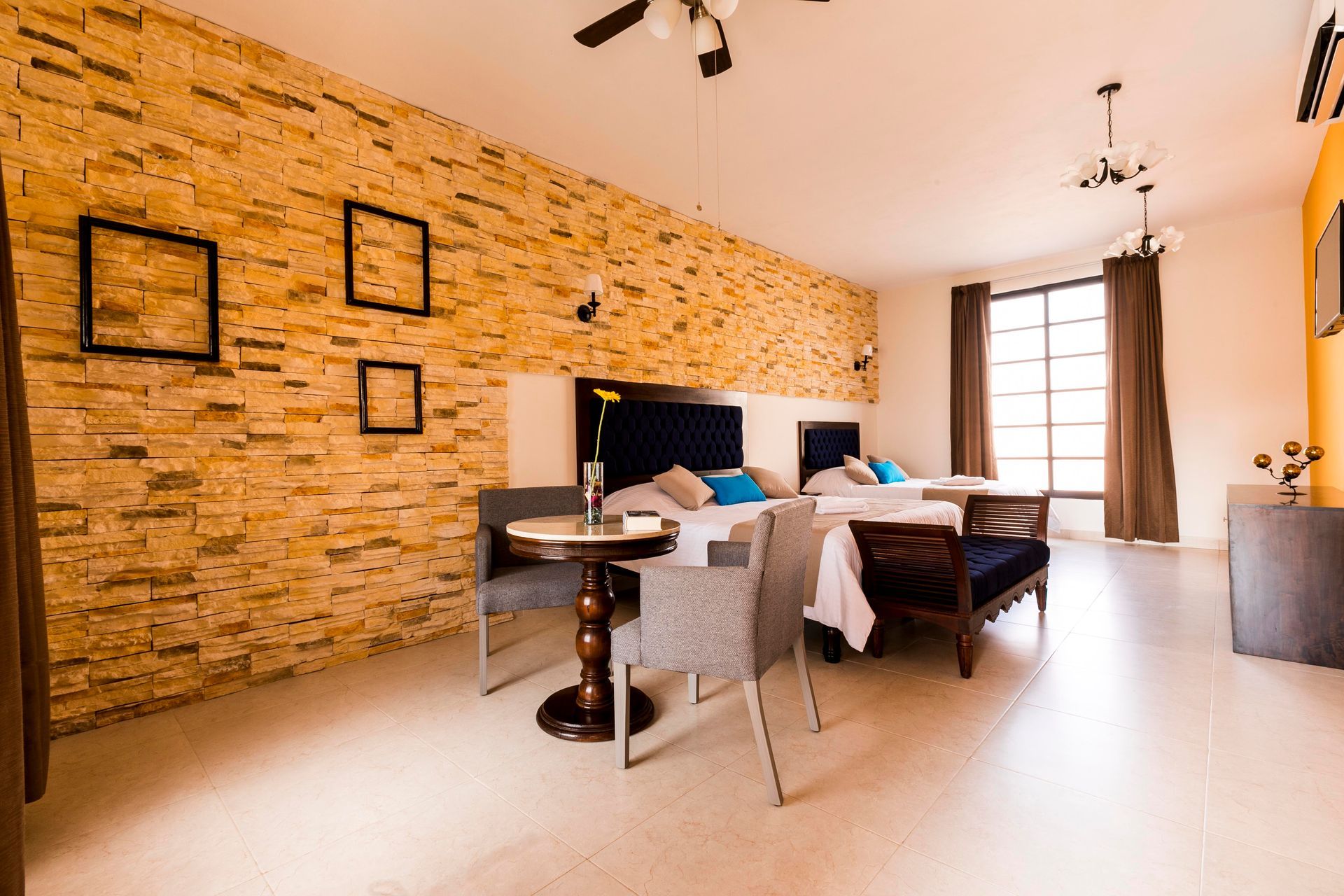 A hotel room with two beds , a table , chairs and a ceiling fan.
