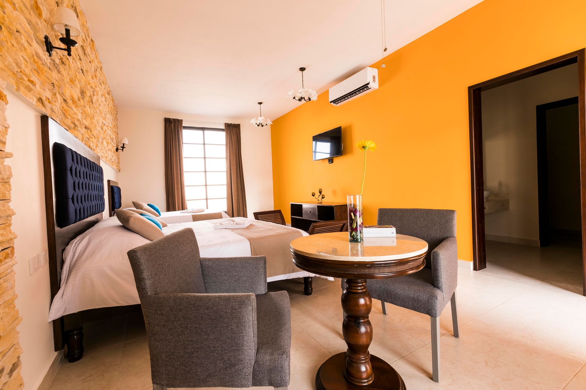 A hotel room with orange walls and a table and chairs