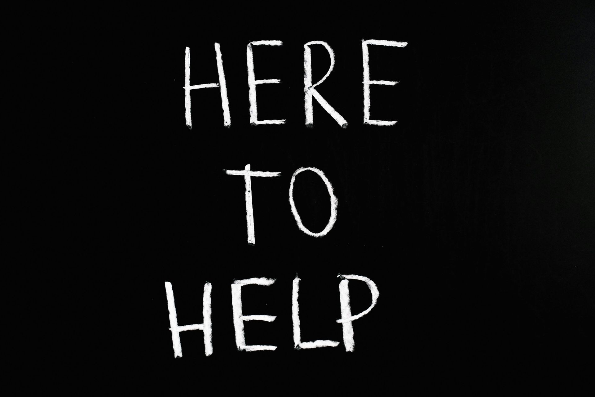 A blackboard with the words here to help written on it