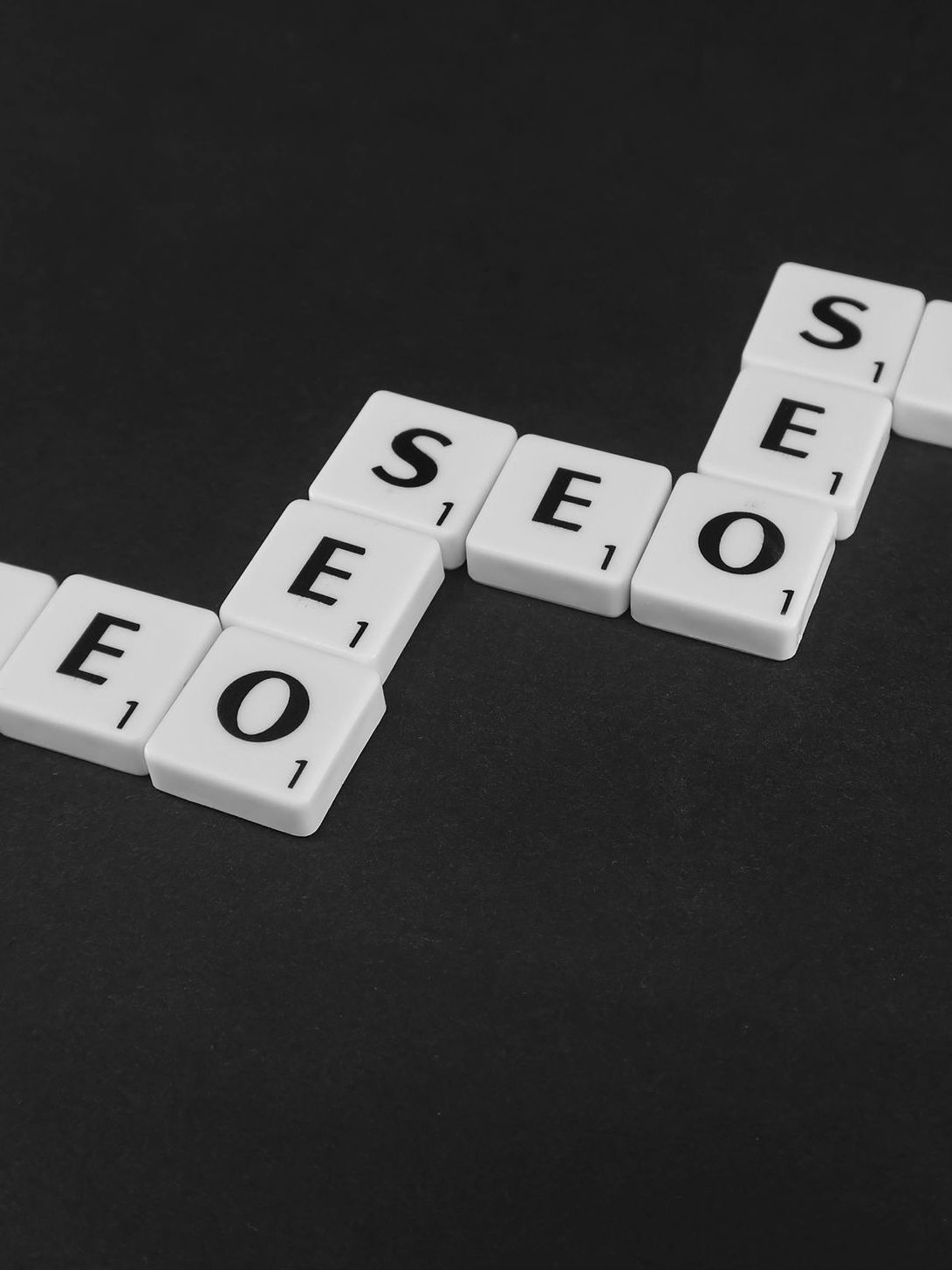 Scrabble tiles spelling out the word linked seo on a black background