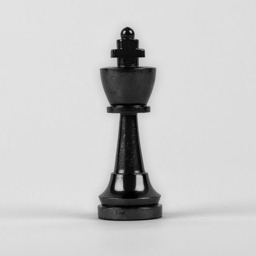 A black king chess piece is sitting on a white surface.