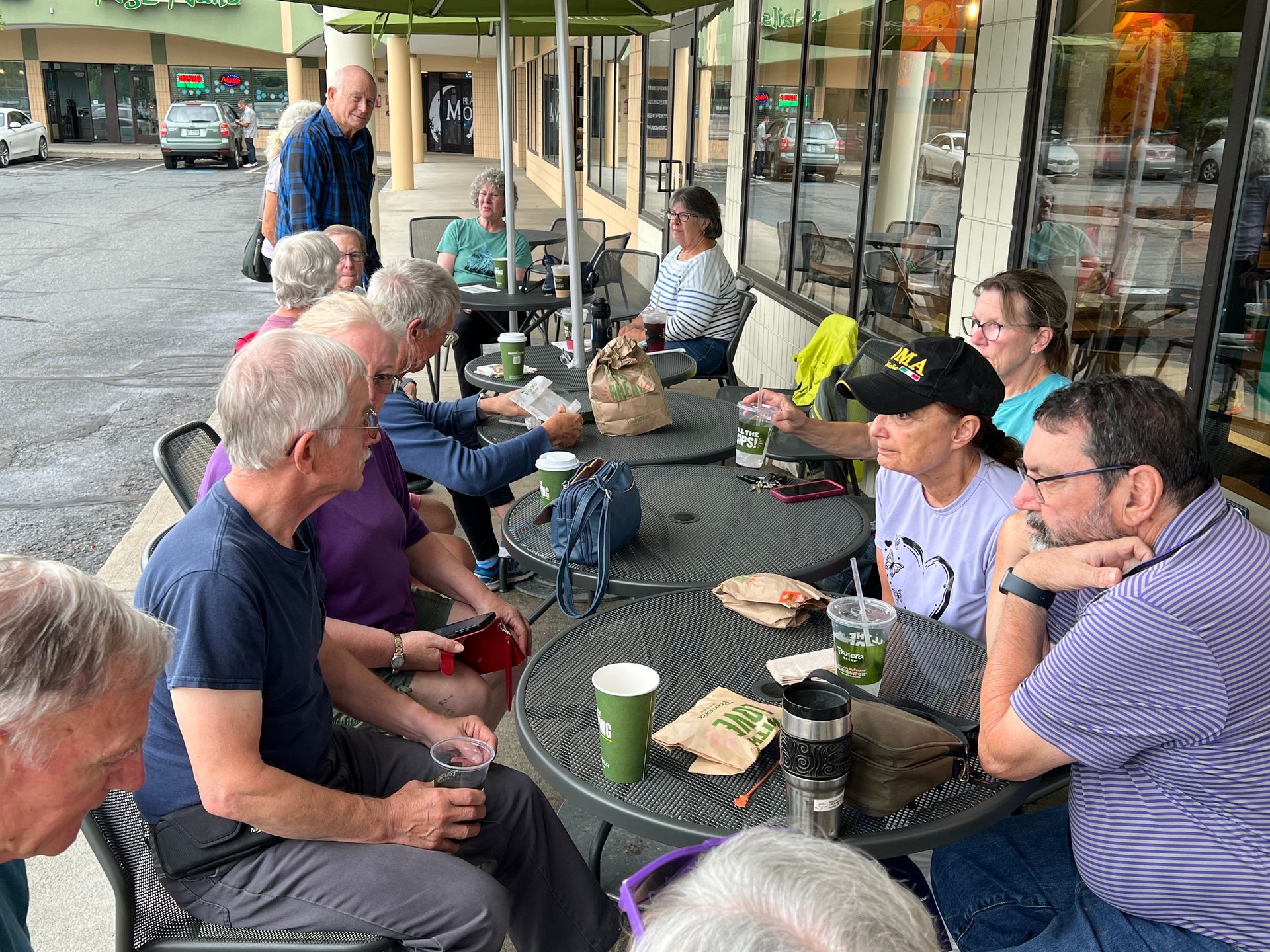 A group of people are sitting at tables outside of a restaurant.