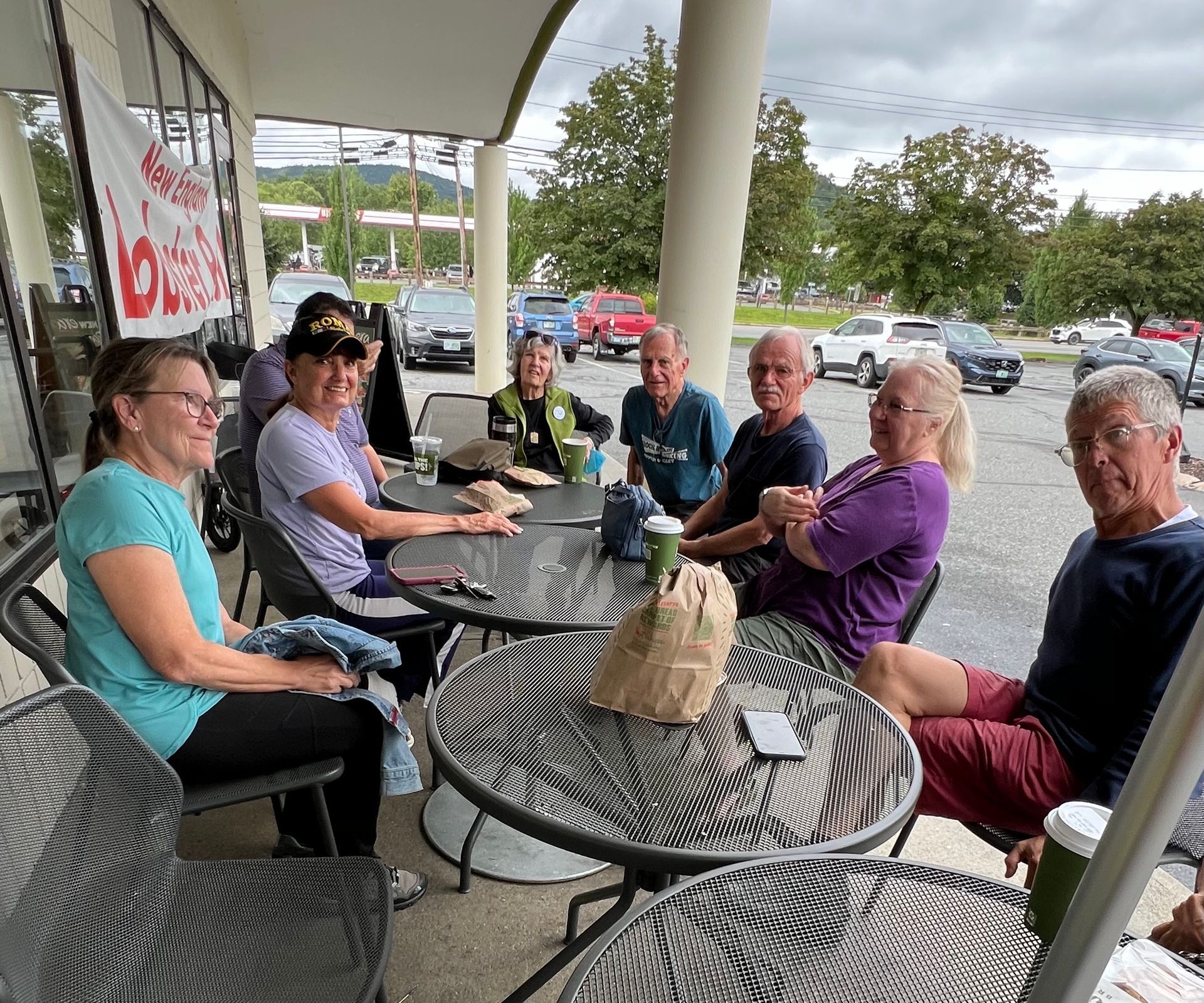 A group of people are sitting around a table in a parking lot.