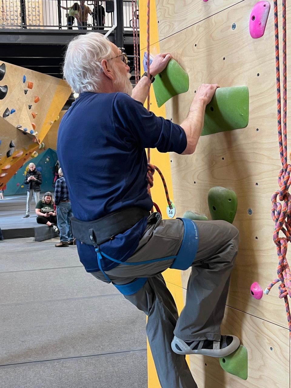 A man in a blue shirt is climbing a climbing wall
