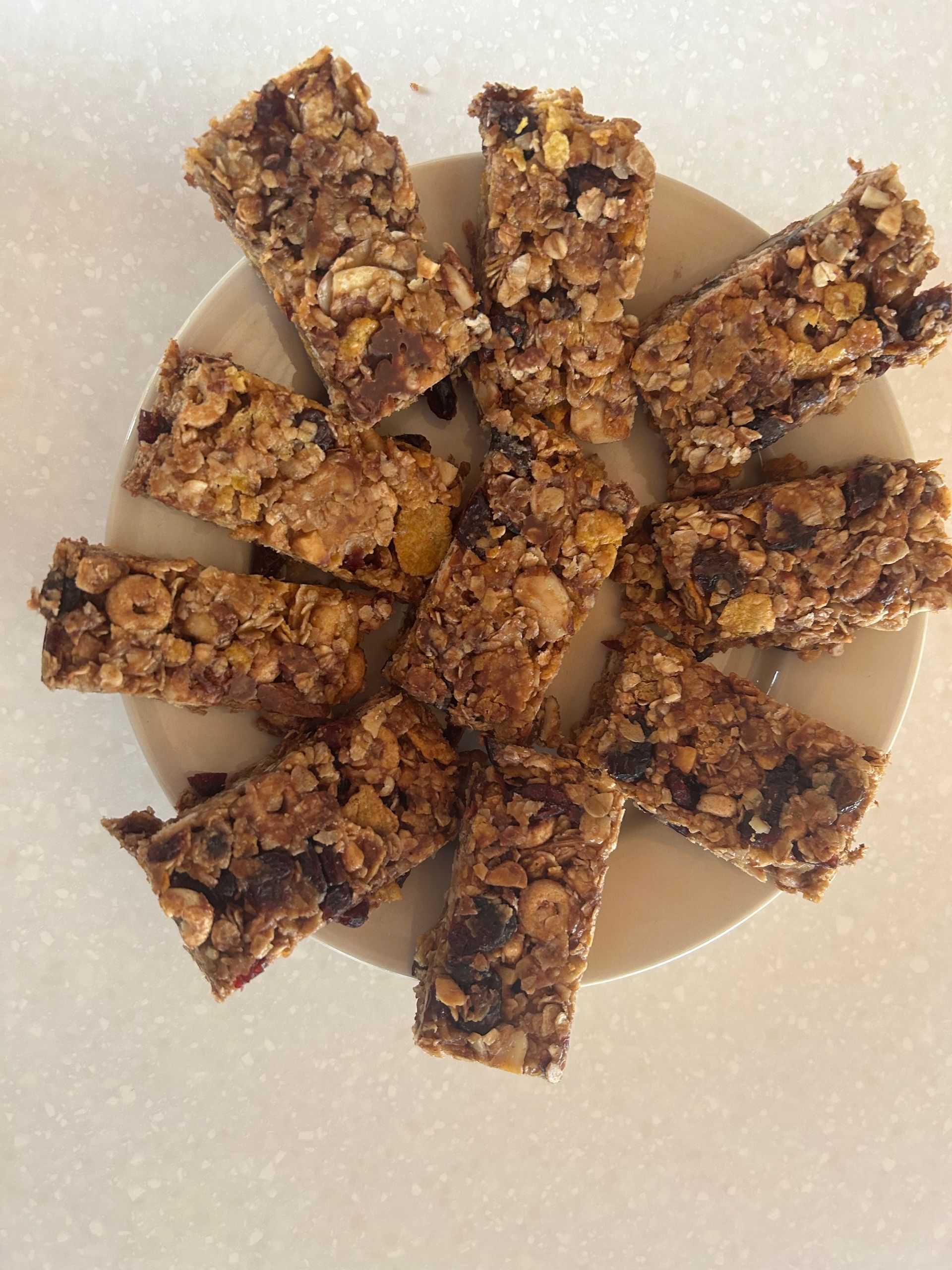 A plate of Peanut Butter granola bars with nuts and chocolate chips on a table.