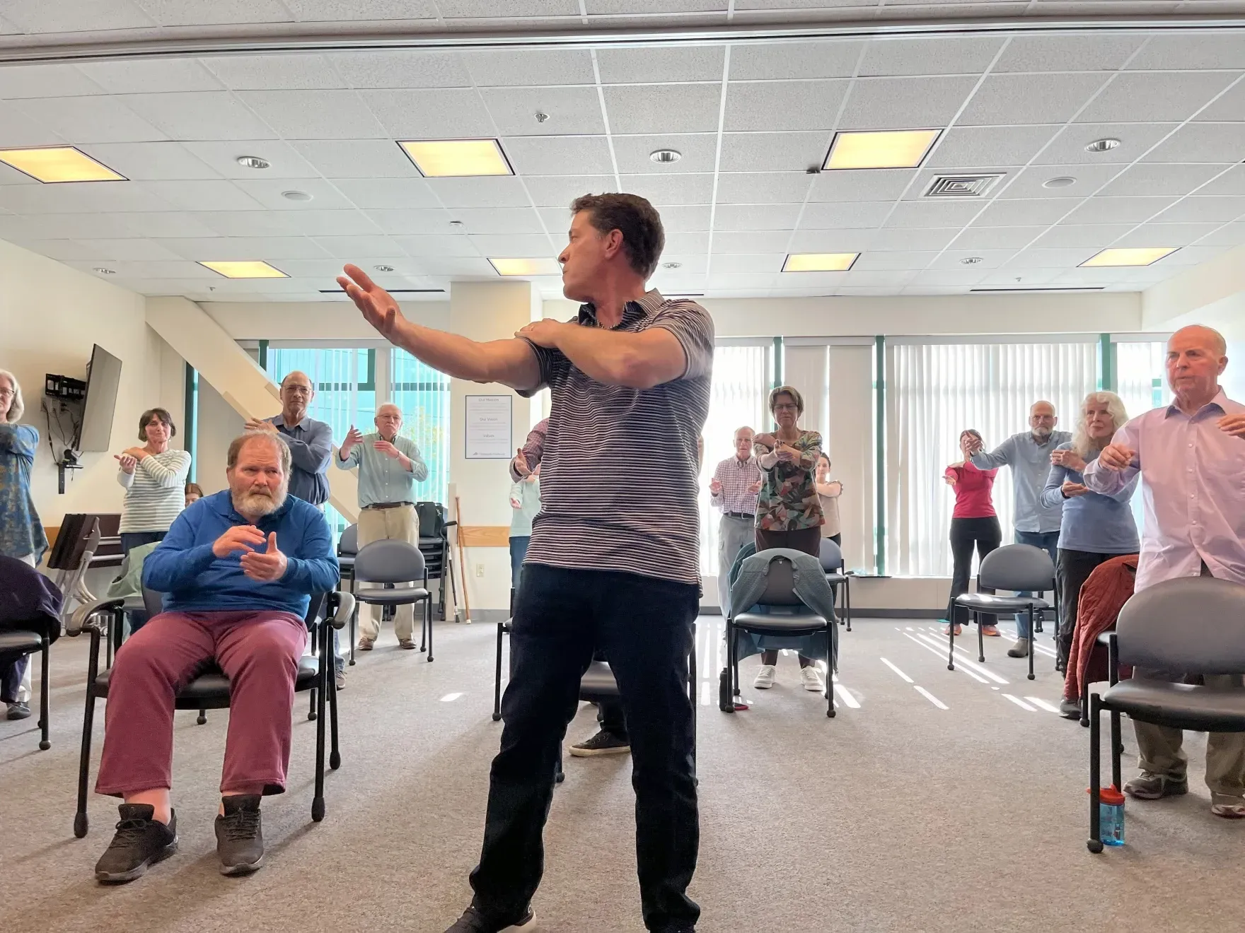 A man is standing in front of a group of people in a room.