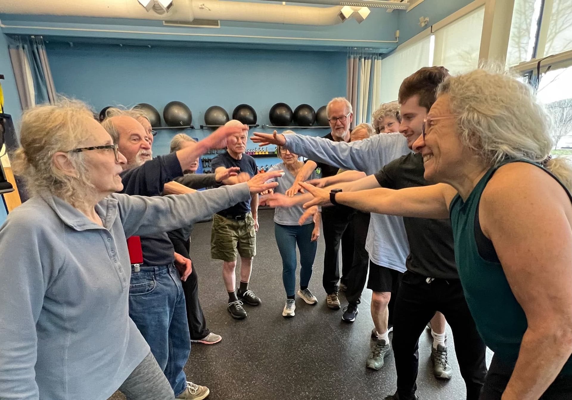 A group of people are stretching their arms in a gym.