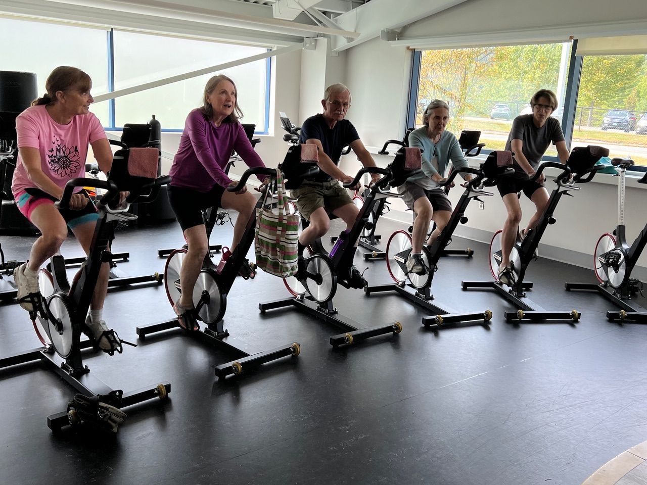 A group of people are riding exercise bikes in a gym.